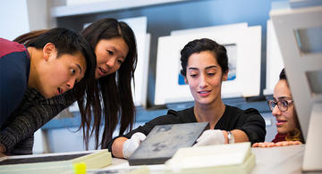students leaning over to see an image revealed