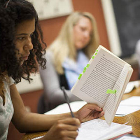 student reading a book and taking notes